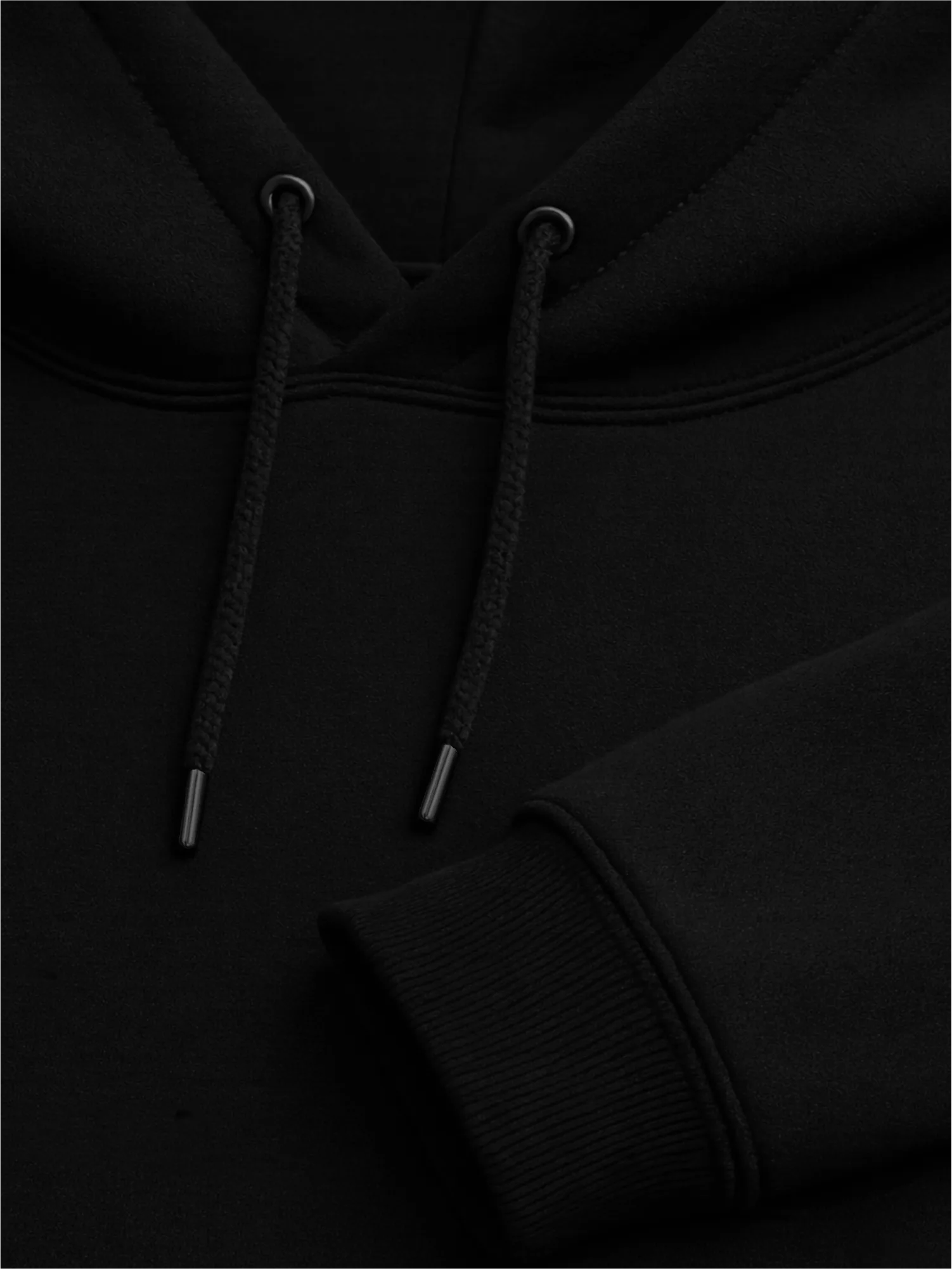 Close-up of black hoodie drawcords, metal eyelets and ribbed cuff