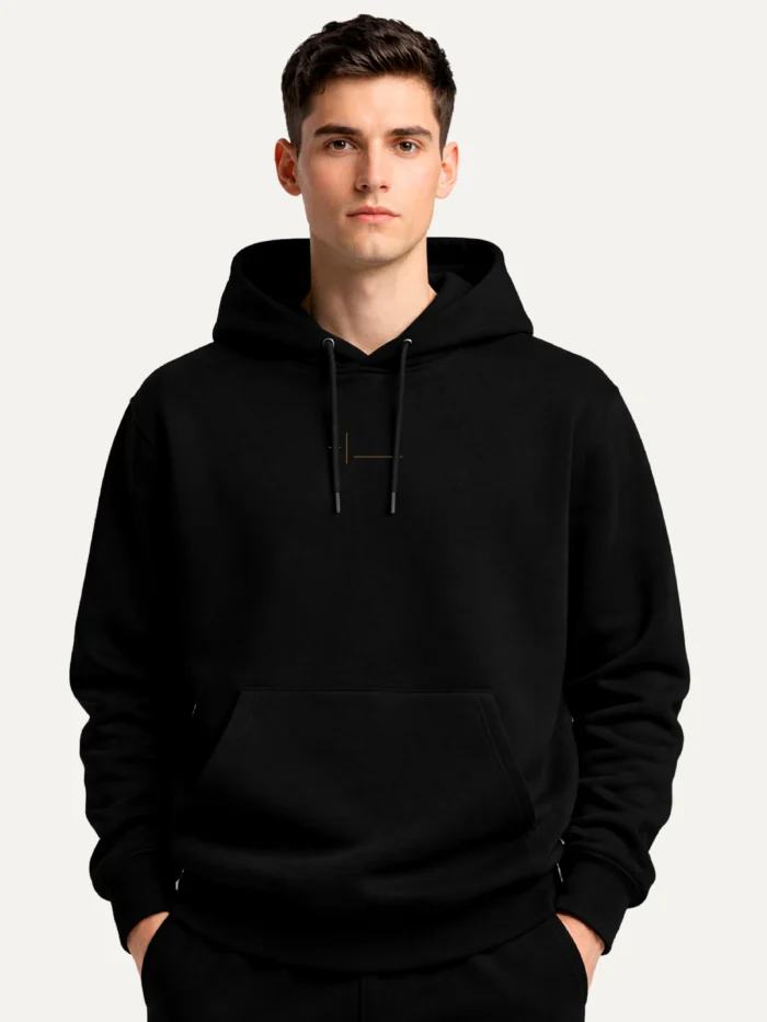 Displaced Ground Organic Cotton Hoodie — Black worn by a male model, showing the reduced Clay Brown centre-chest artwork.